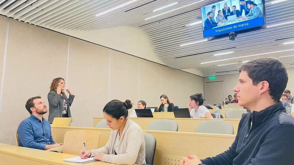Adriana facilita una clase presencial con participantes atentos en el aula